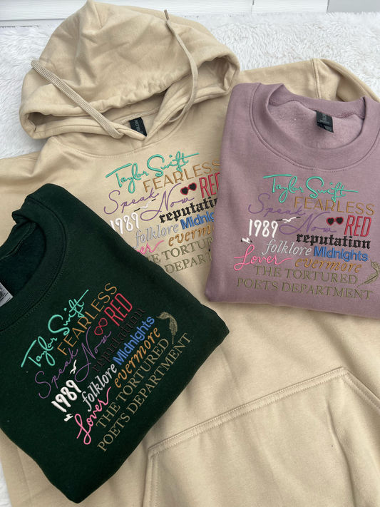 Taylor Swifts albums all embroidered onto a sweatshit using their individual colours and fonts specific to their album covers