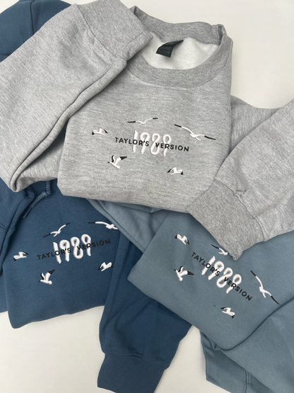 Taylor swifts 1989 Album title embroidered onto a stone blue, indigo blue and light grey coloured hoodie