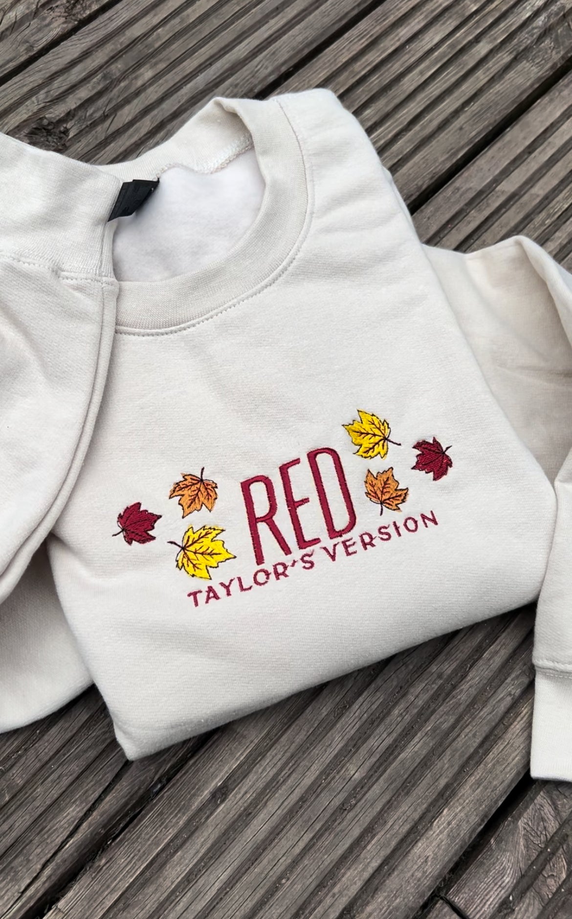 taylor swifts red album title embroidered in the same colour and font appeared on the album cover alongside some autumn leaves on a sandcoloured hoodie