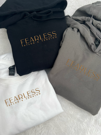 taylor swifts fearless album title embroidered on a black , white and dark grey hoodie